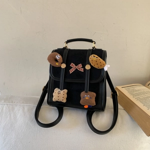 Detail of black mini backpack with cute cartoon plush pins and red checkered bow