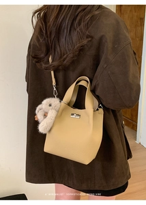 Detail of beige bucket bag with silver twist lock and cute grey plush bunny charm