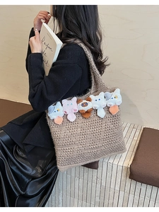 Detail of a brown knit tote bag featuring five adorable 3D plush cats on a wooden background
