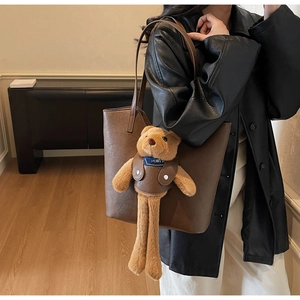 Detail der dunkelbraunen Leder-Shopper-Tasche mit einem Teddybär-Anhänger