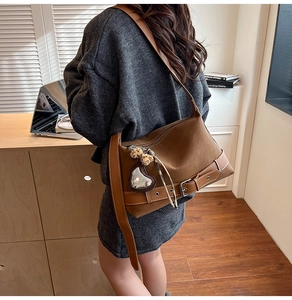 Close-up of vintage brown tote bag with leather belt straps and leopard print charm