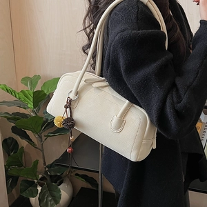Dettaglio borsa bowling in pelle testurizzata bianco crema con ciondolo nappina