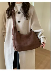Vue détaillée du sac hobo en daim marron avec sa large bandoulière sur un manteau