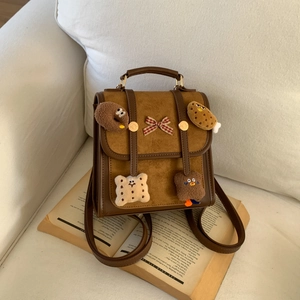 Detailed view of mini brown leather backpack with cute plush charms on open book
