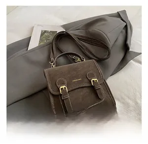 Detail of brown vintage crossbody bag showing textured pebble grain and golden buckle