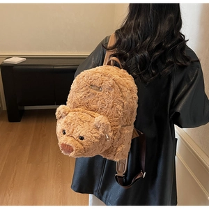 Détail d'un sac à dos ours en peluche avec fourrure brune douce et logo métallique