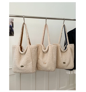 Dettaglio di borse tote in peluche color crema con fodere marrone e blu e etichetta handmade