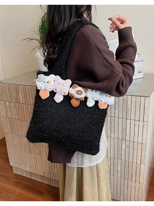 Detail of black knit tote bag featuring colorful plush cat dolls and textured yarn finish