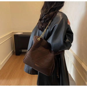 Detail of dark brown suede bucket bag with gold chain strap and quilted stitching