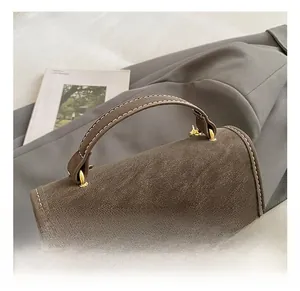 Detail of vintage brown leather handbag featuring white stitching and gold metal D-rings