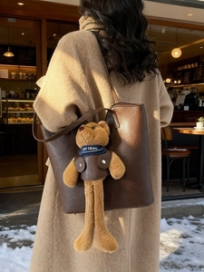 Braune Leder-Tote-Bag mit Bärenanhänger in einer stylischen Rückansicht im Freien