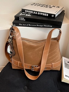 Retro brown suede tote bag with decorative buckle and heart mirror charm on a cushion