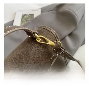Detail of vintage brown leather backpack showing gold swivel hook and reinforced stitching