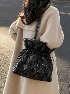 Quilted shiny black bucket shoulder bag with drawstring closure in sunset street setting