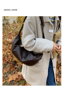 Model wearing dark brown oversized crescent bag over a grey wool coat in autumn setting
