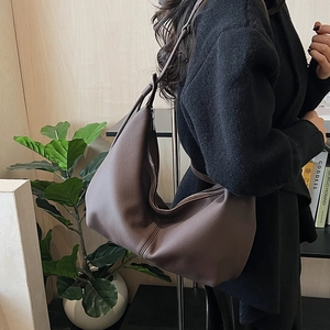 Detail of a brown leather Hobo bag with lychee texture and adjustable strap on a shoulder
