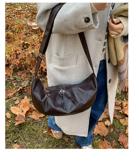 Outdoor shot of a dark brown matte leather hobo bag with wide strap on a winter coat