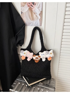 Detail of black plush tote bag featuring five colorful stuffed cat plushies on surface