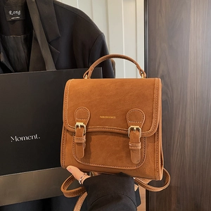 Detail of vintage brown matte leather backpack with gold metal buckles and top handle