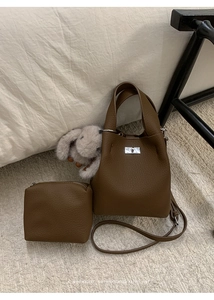 Detail of dark brown lychee leather bucket bag with silver twist lock and rabbit charm