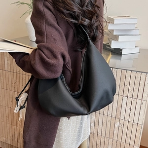Detail of black leather dumpling bag showing large capacity and soft pebbled texture on model