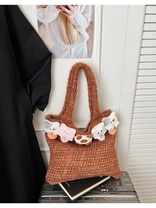 Detail of brown knitted tote bag with cute plush animal charms on silver suitcase