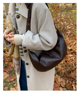 Dettaglio della borsa hobo in pelle marrone scuro con nappa abbinata a un cappotto beige