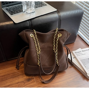 Detail of coffee brown tote bag featuring quilted texture and golden chain strap