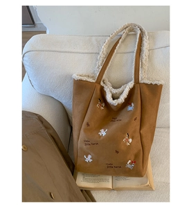 Dettaglio della borsa in pelle scamosciata con bordo in shearling e ricamo a pony