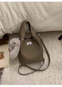 Detail of coffee brown pebble leather bucket bag with silver lock and plush bunny charm