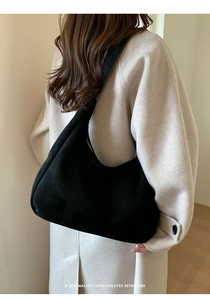 Sac fourre-tout minimaliste en daim noir avec bandoulière rétro porté à l'épaule par un mannequin