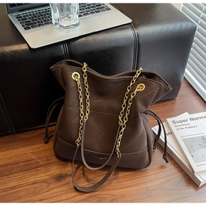 Macro detail of brown quilted leather bucket bag featuring gold chain and drawstring