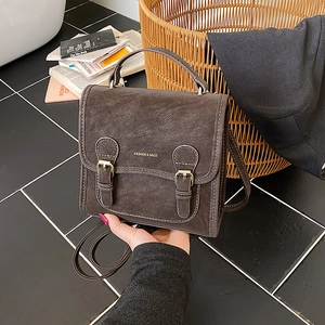 Detail of dark brown matte leather shoulder bag with vintage magnetic buckle and gold logo