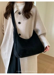 Close-up of minimalist black suede hobo bag with wide shoulder strap on a model