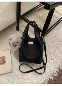 Detail view of black lychee grain leather bucket bag with silver lock and plush bunny