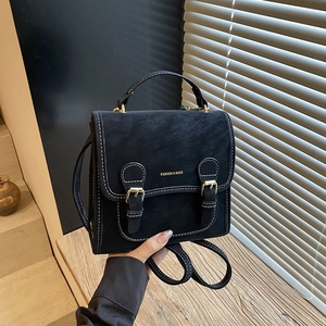 Close-up of black vintage backpack with white contrast stitching and golden buckles