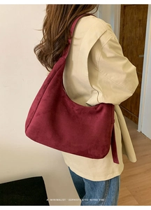 Detail of burgundy faux suede hobo bag with minimalist design and retro aesthetic