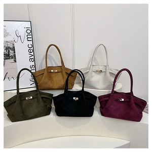 Detailed view of five multi-colored suede tote bags displayed on a white podium