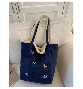 Dettaglio borsa tote in velluto a coste blu scuro con ricami e fodera in pile