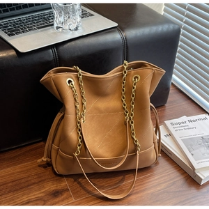 Detail of tan quilted faux leather tote bag with gold chain straps in office setting