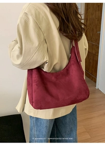 Détail du sac hobo en daim bordeaux avec large bandoulière et style rétro minimaliste