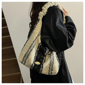 Detail of striped faux fur tote bag with handmade metal plaque and woven strap