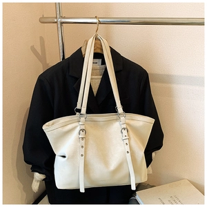 Detail of adjustable strap buckles and fine grain texture on beige tote shoulder bag