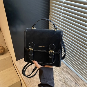 Detail of black vintage backpack with white stitching and golden buckles with hand strap