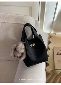 Detail of black pebbled leather bucket bag with silver turn-lock and rabbit charm