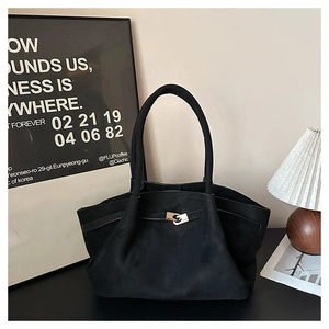 Detail of minimalist black matte suede tote bag with decorative metal lock on wood table