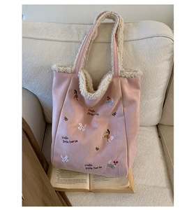 Dettaglio della borsa a secchiello rosa con ricami di cartoni animati e fodera in pile