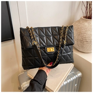 Détail du sac fourre-tout noir matelassé avec fermoir doré et bandoulière en chaîne
