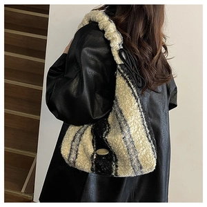 Detail of plush black and white striped hobo bag with metal logo and black drawstring