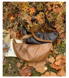 Detail view of retro pleated crescent bags with fringe zippers on autumn leaves